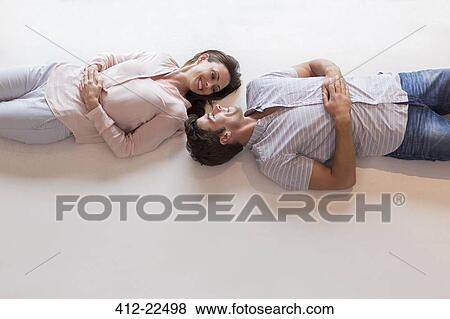 Couple looking at each other while lying on table View Large Photo Image Stock Photo - Couple looking at each other while lying on table. Fotosearch