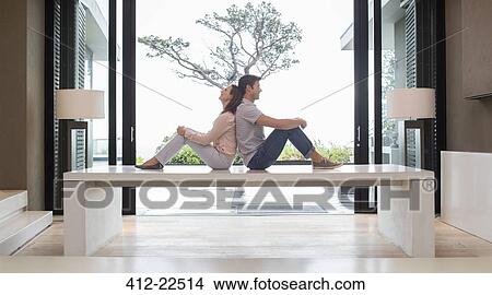 Couple sitting back to back on table View Large Photo Image Picture - Couple sitting back to back on table. Fotosearch