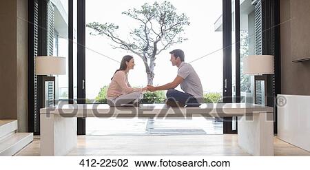 Couple sitting on table face to face and holding hands, tree seen through patio door in background View Large Photo Image Stock Image - Couple sitting on table face to face and holding hands, tree seen through patio door in background. Fotosearch