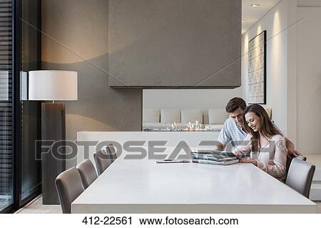 Stock Image - Couple using tablet pc in dining room. Fotosearch
