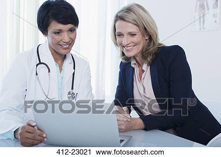 Doctor and patient using laptop in hospital office View Large Photo Image Stock Image - Doctor and patient using laptop in hospital office. Fotosearch