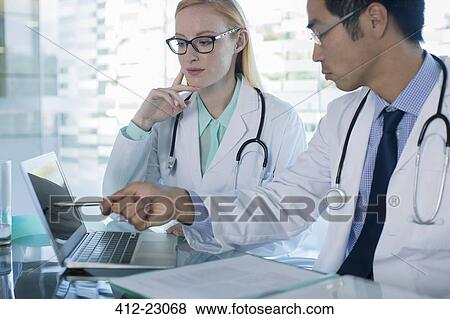 Stock Photo - Doctors using laptop and discuss patient's treatment. Fotosearch
