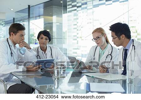 Doctors using laptop and discussing patient's treatment View Large Photo Image Picture - Doctors using laptop and discussing patient's treatment. Fotosearch
