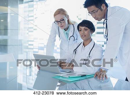 Stock Photo - Doctors using laptop and discussing patient's treatment. Fotosearch