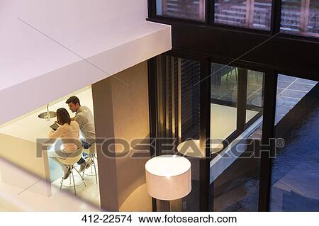 Elevated view of couple using tablet pc in dining room View Large Photo Image Picture - Elevated view of couple using tablet pc in dining room. Fotosearch