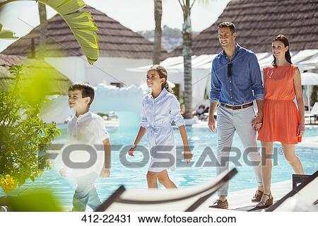 Stock Image - Family with two children walking together by swimming pool. Fotosearch