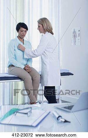 Female doctor examining her patient in office, laptop, otoscope, file and glasses on desk in foreground View Large Photo Image Stock Image - Female doctor examining her patient in office, laptop, otoscope, file and glasses on desk in foreground. Fotosearch