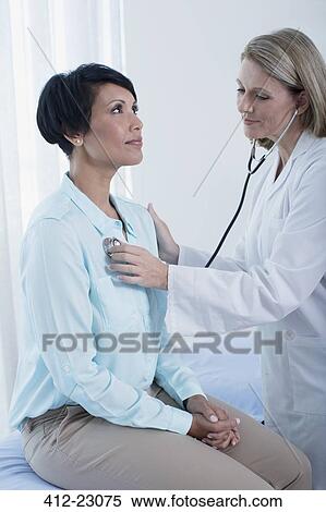 Female doctor examining her patient with stethoscope in office View Large Photo Image Stock Photography - Female doctor examining her patient with stethoscope in office. Fotosearch