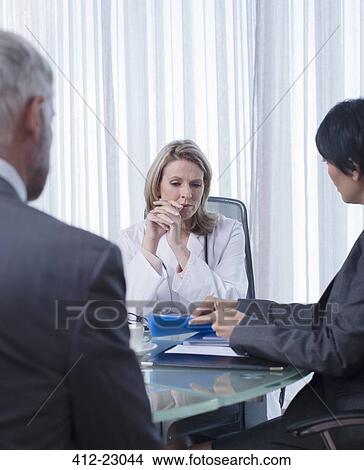 Female doctor, man and woman sitting at table in office View Large Photo Image Picture - Female doctor, man and woman sitting at table in office. Fotosearch