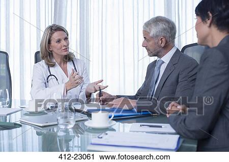 Female doctor, man and woman talking at table in conference room View Large Photo Image Stock Image - Female doctor, man and woman talking at table in conference room. Fotosearch