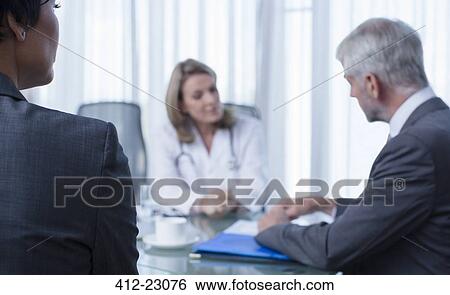 Female doctor, man and woman talking at table in conference room View Large Photo Image Stock Photograph - Female doctor, man and woman talking at table in conference room. Fotosearch