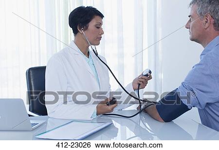 Female doctor taking patient's blood pressure in office View Large Photo Image Stock Photograph - Female doctor taking patient's blood pressure in office. Fotosearch
