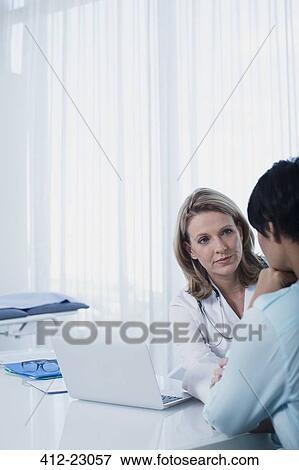 Female doctor talking to woman at desk in office View Large Photo Image Stock Photo - Female doctor talking to woman at desk in office. Fotosearch
