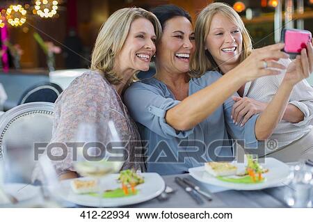Female friends taking selfie in restaurant View Large Photo Image Picture - Female friends taking selfie in restaurant. Fotosearch