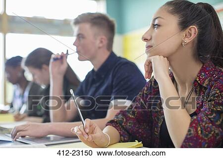 Stock Image - Female student contemplating in classroom. Fotosearch