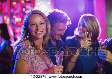 Friends with champagne flutes having fun in nightclub View Large Photo Image Stock Photograph - Friends with champagne flutes having fun in nightclub. Fotosearch
