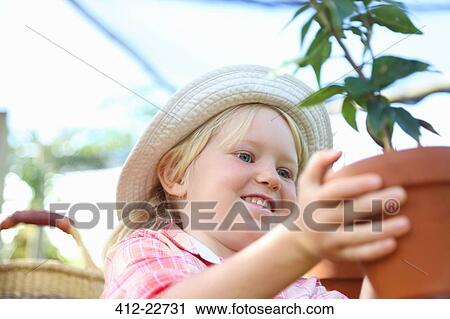 Girl wearing straw hat holding potted plant View Large Photo Image Stock Image - Girl wearing straw hat holding potted plant. Fotosearch
