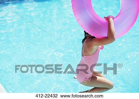 Stock Image - Girl with pink inflatable ring jumping into swimming pool. Fotosearch