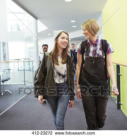 Stock Image - Group of cheerful students walking in corridor. Fotosearch
