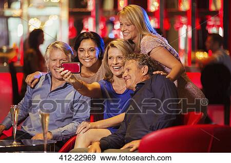 Stock Photo - Group of mature friends taking selfie in nightclub. Fotosearch