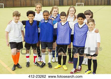 Stock Image - Group portrait of children wearing sport uniforms standing in school gym. Fotosearch