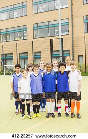 Stock Photo - Group portrait of children wearing sport uniforms standing in front of school. Fotosearch