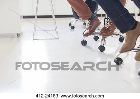 Legs of business people sitting on chairs in office View Large Photo Image Stock Image - Legs of business people sitting on chairs in office. Fotosearch