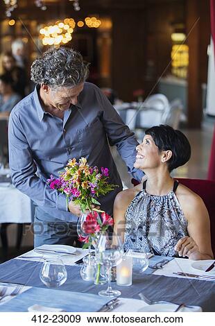 Man giving bouquet of flowers to woman in restaurant View Large Photo Image Stock Photo - Man giving bouquet of flowers to woman in restaurant. Fotosearch