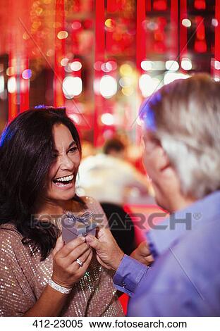 Man giving gift to smiling mature woman in nightclub View Large Photo Image Stock Photography - Man giving gift to smiling mature woman in nightclub. Fotosearch