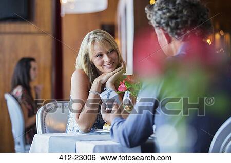 Man giving gift to smiling woman at restaurant table View Large Photo Image Stock Photograph - Man giving gift to smiling woman at restaurant table. Fotosearch