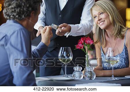 Stock Image - Man paying with credit card in restaurant. Fotosearch