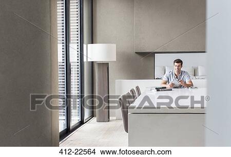 Man sitting at table and texting in dining room View Large Photo Image Picture - Man sitting at table and texting in dining room. Fotosearch