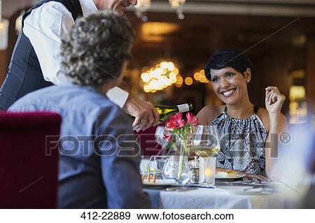 Mature couple in restaurant, waiter pouring white wine View Large Photo Image Stock Photo - Mature couple in restaurant, waiter pouring white wine. Fotosearch