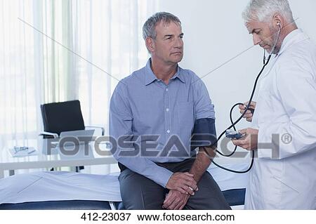 Stock Photo - Mature doctor taking patient's blood pressure in office. Fotosearch