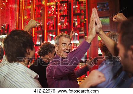Men high fiving each other in nightclub View Large Photo Image Stock Photograph - Men high fiving each other in nightclub. Fotosearch
