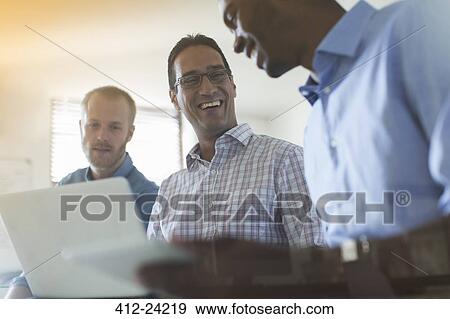 Stock Photo - Men using digital tablet and laptop in office. Fotosearch