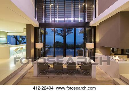 Picture - Modern dining room with fireplace and kitchen at night. Fotosearch