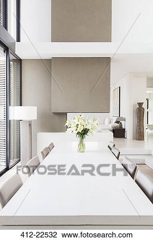 Modern white and beige dining room with large table and lilies in vase View Large Photo Image Stock Image - Modern white and beige dining room with large table and lilies in vase. Fotosearch