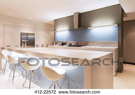 Modern white kitchen with kitchen island and stools illuminated at night View Large Photo Image Stock Image - Modern white kitchen with kitchen island and stools illuminated at night. Fotosearch