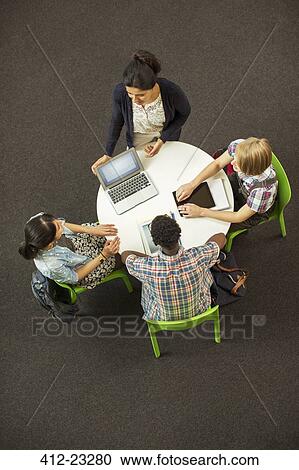 Overhead view of student doing homework at round table, using laptop and digital tablet View Large Photo Image Stock Image - Overhead view of student doing homework at round table, using laptop and digital tablet. Fotosearch