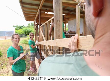 Stock Photo - People building wooden house frame together. Fotosearch
