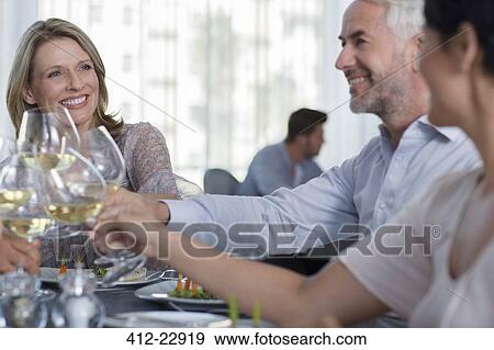 People raising a toast with white wine in restaurant View Large Photo Image Stock Photo - People raising a toast with white wine in restaurant. Fotosearch
