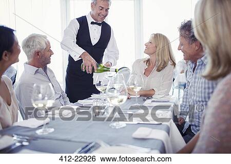 People sitting at restaurant table, waiter pouring white wine View Large Photo Image Stock Photograph - People sitting at restaurant table, waiter pouring white wine. Fotosearch