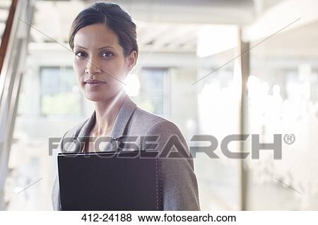 Portrait of businesswoman holding documents in office corridor View Large Photo Image Stock Photo - Portrait of businesswoman holding documents in office corridor. Fotosearch