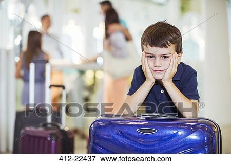 Portrait of pensive boy leaning on suitcase in hotel lobby View Large Photo Image Stock Photo - Portrait of pensive boy leaning on suitcase in hotel lobby. Fotosearch