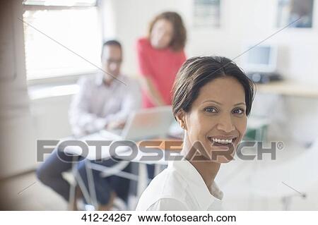 Portrait of smiling businesswoman in office, colleagues working in background View Large Photo Image Stock Photo - Portrait of smiling businesswoman in office, colleagues working in background. Fotosearch