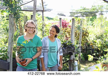 Portrait of smiling couple standing in sunny greenhouse with potted plant View Large Photo Image Stock Photo - Portrait of smiling couple standing in sunny greenhouse with potted plant. Fotosearch