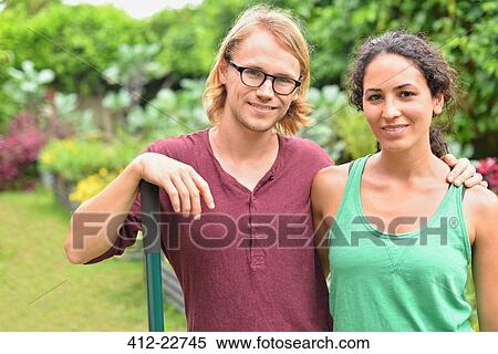 Stock Photography - Portrait of smiling couple standing in garden. Fotosearch