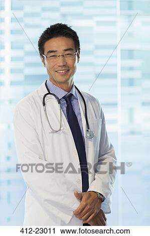 Portrait of smiling doctor wearing glasses and lab coat standing in hospital View Large Photo Image Stock Image - Portrait of smiling doctor wearing glasses and lab coat standing in hospital. Fotosearch