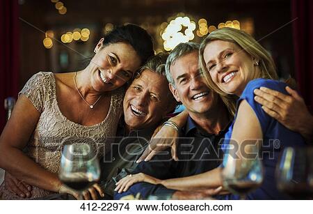 Portrait of smiling mature couples sitting together in restaurant View Large Photo Image Picture - Portrait of smiling mature couples sitting together in restaurant. Fotosearch